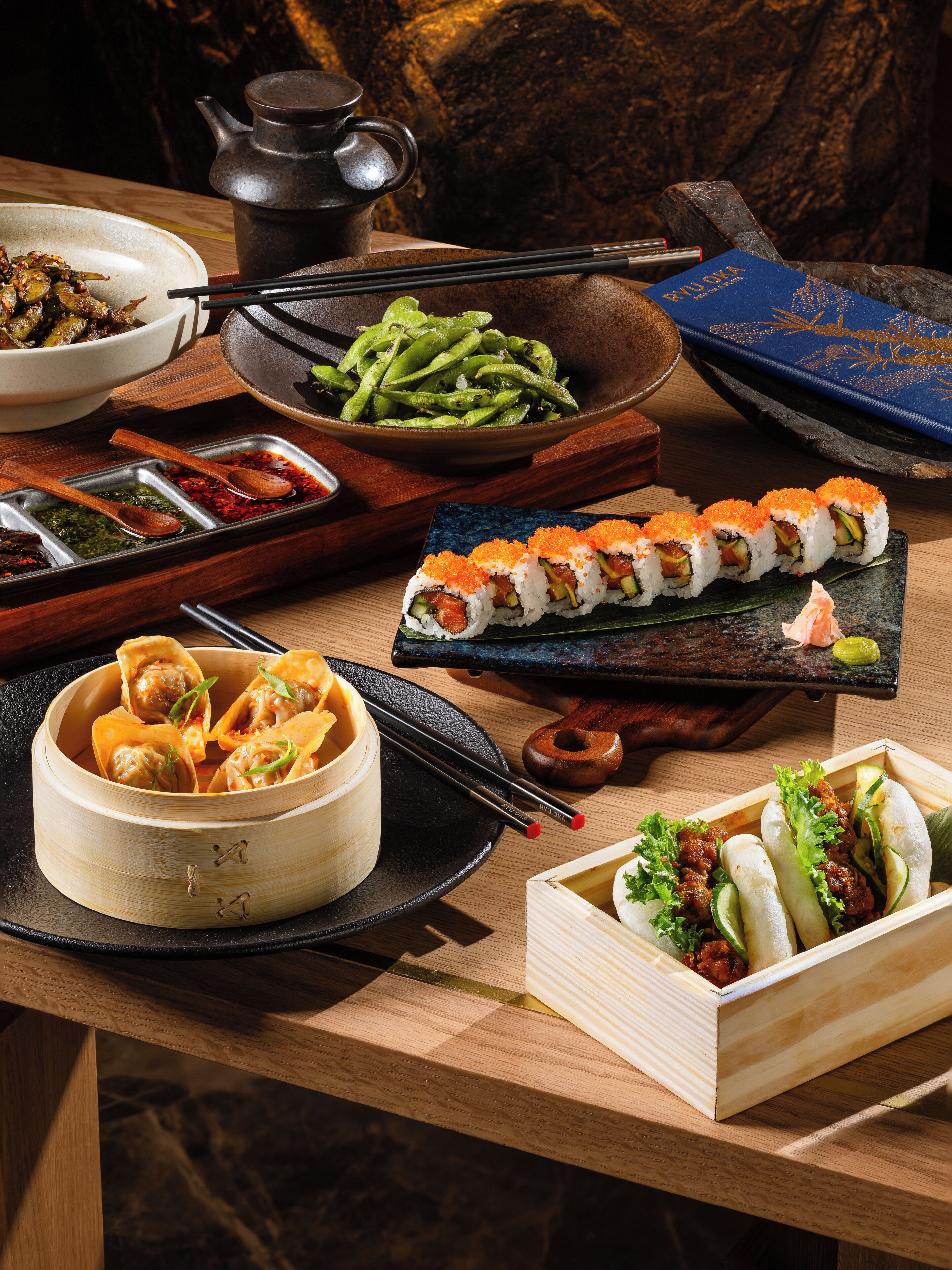 A variety of Japanese dishes including sushi, dumplings, and pickled vegetables on a wooden table.