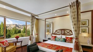 A spacious bedroom with a large bed, a view of mountains, and a cozy seating area. - The Grand Dragon Ladakh (Leh)