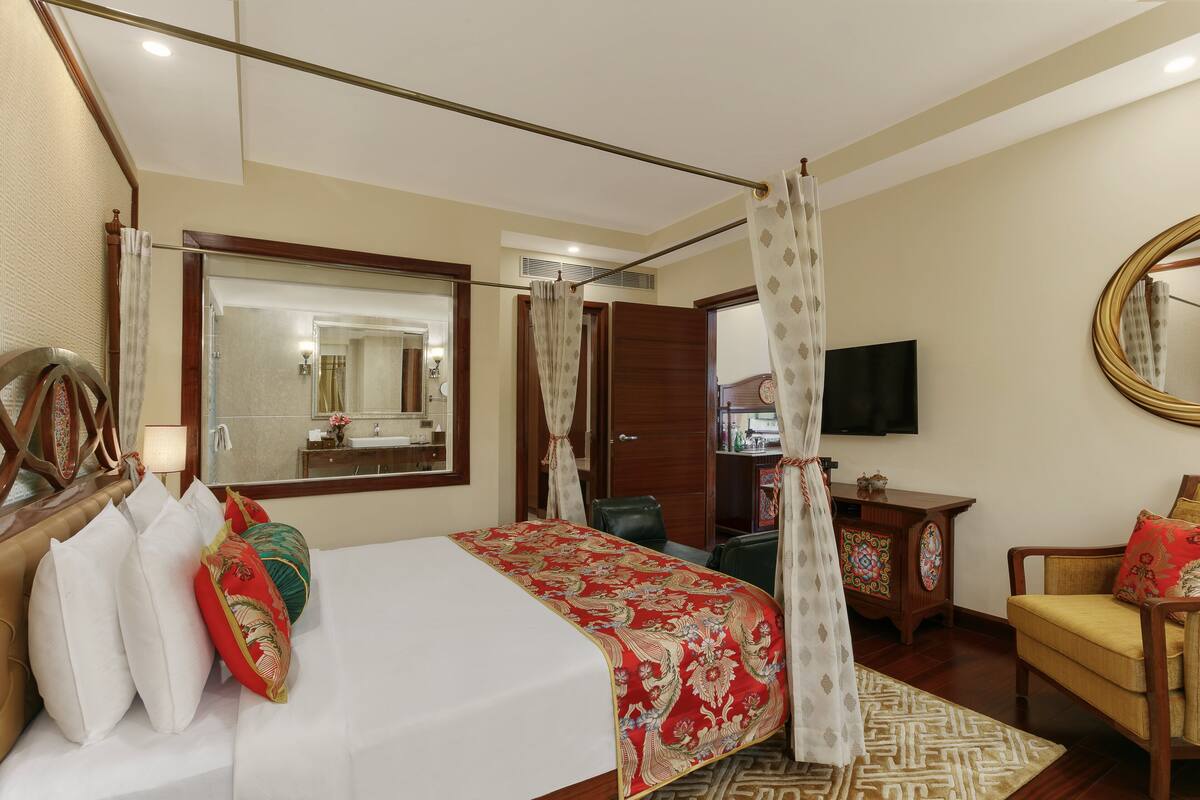 A hotel room with a bed, a chair, a television, and a mirror.