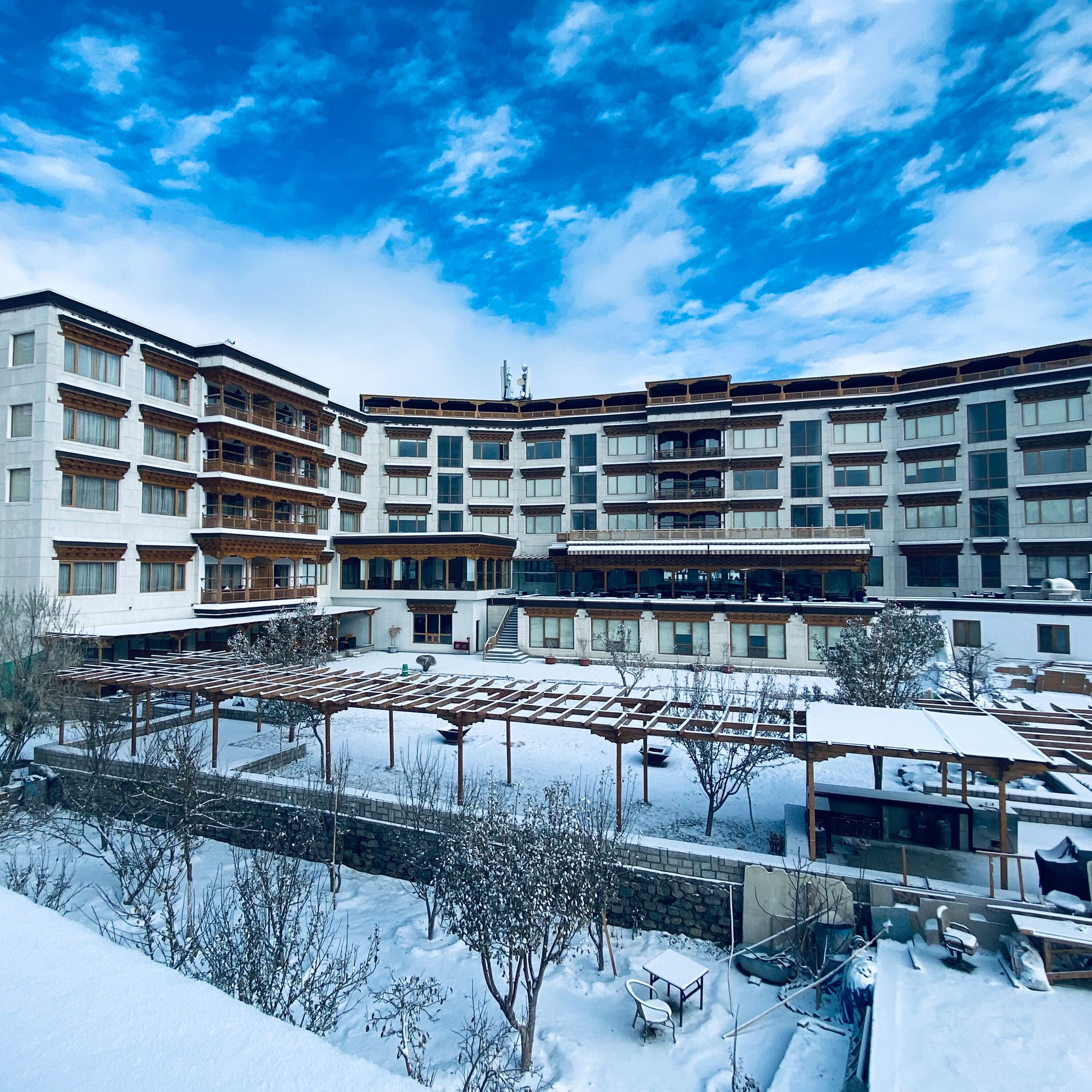 A multi-story hotel with a courtyard, outdoor seating, and a snow-covered ground.