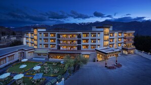 A multi-story hotel with a courtyard featuring outdoor seating and a decorative gazebo. - The Grand Dragon Ladakh (Leh)