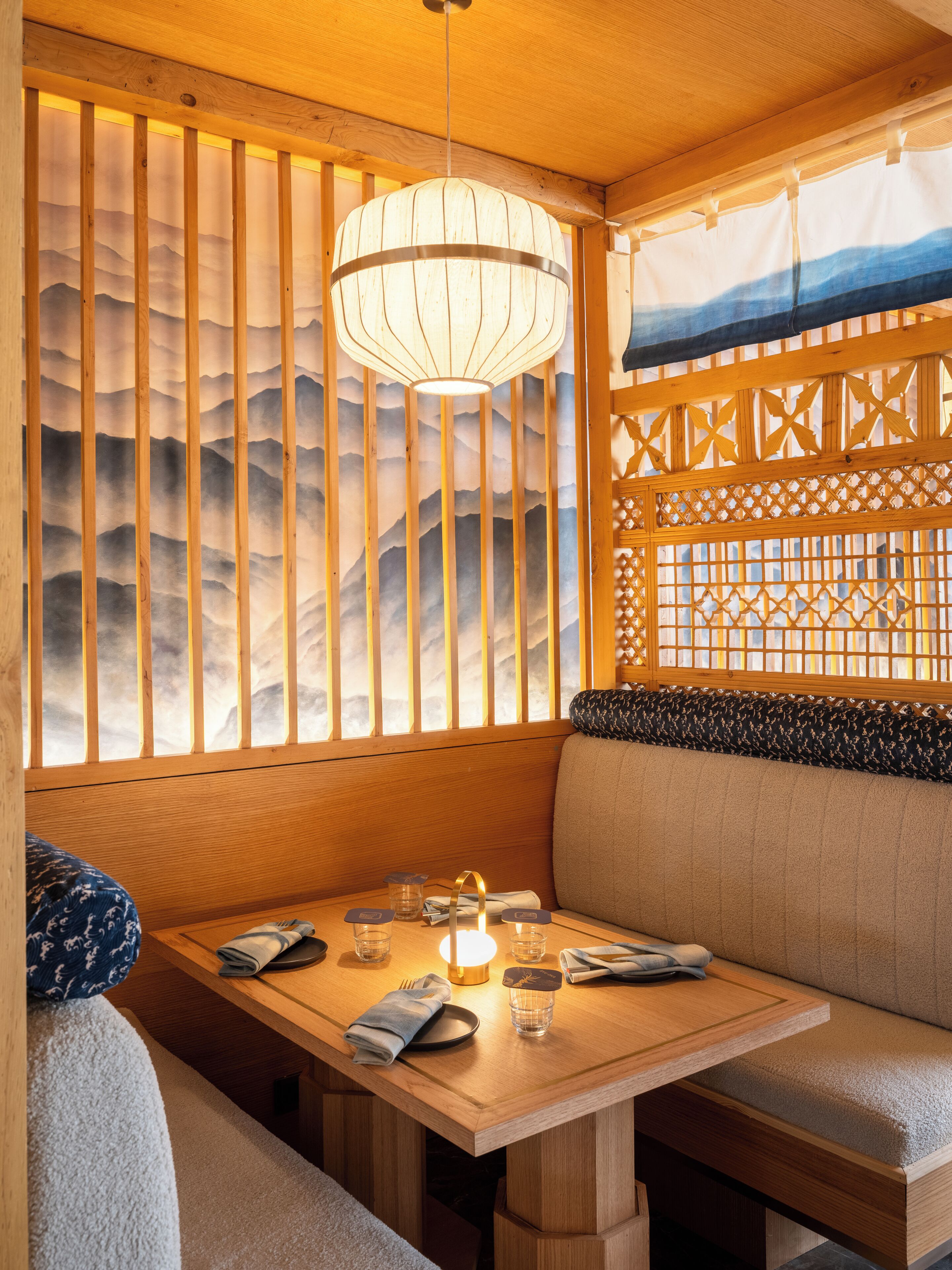 Interior de madera con una mesa de comedor, asientos acolchados y una pared decorativa con listones verticales.