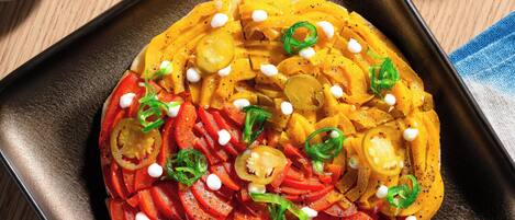 A dish with sliced vegetables and cheese on a square plate.