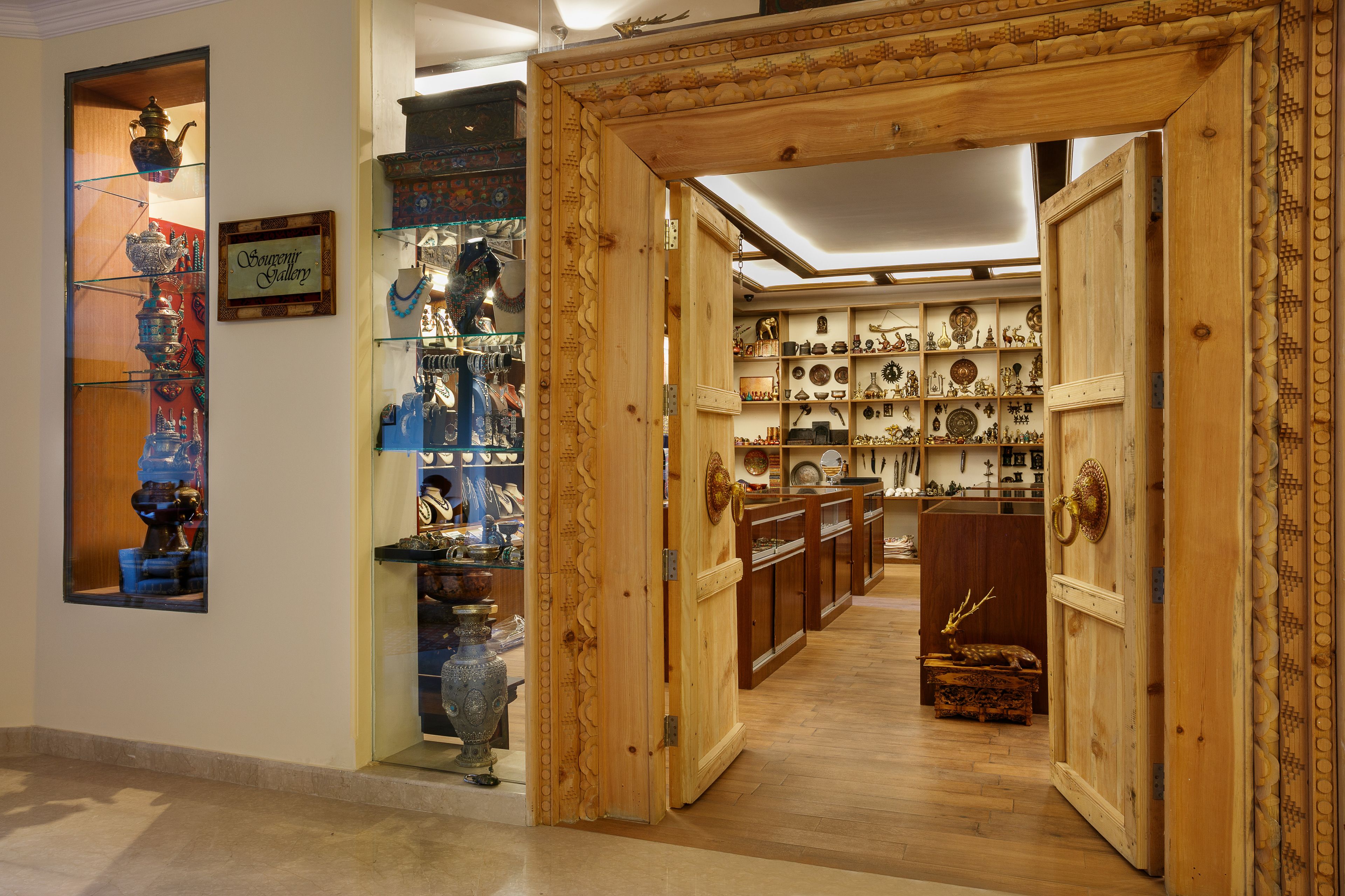 An interior with a wooden door leading to a room filled with decorative items and a glass display case with various objects.