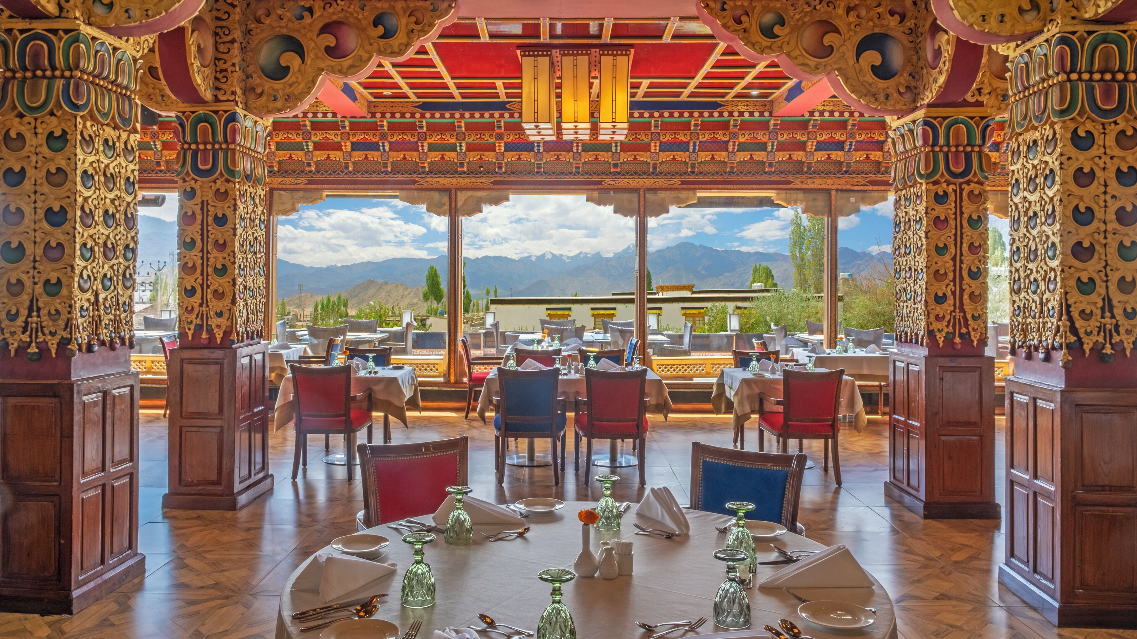 A restaurant with ornate decor, tables set for dining, and a mountain view.