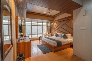 Quarto com cabeceira de madeira, cama com almofadas, escrivaninha com espelho e janela com cortinas.