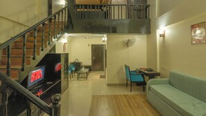 Un espacio habitable en varios niveles, con escalera, televisor de pantalla plana, comedor y sofá.