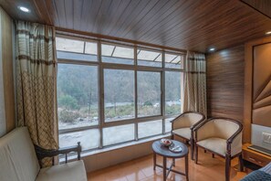A room with a large window, two chairs, a small table, and a bed. - Dynasty Resort (Nainital)