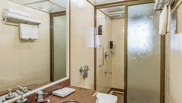Une salle de bain avec un lavabo sur un plan de travail en granit, un miroir, des toilettes et une douche à parois de verre.