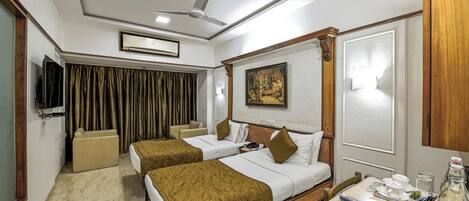 Habitación de hotel con dos camas, televisión, ventilador de techo y un cuadro en la pared.