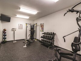 A gym with exercise equipment, a wall-mounted TV, and a poster.