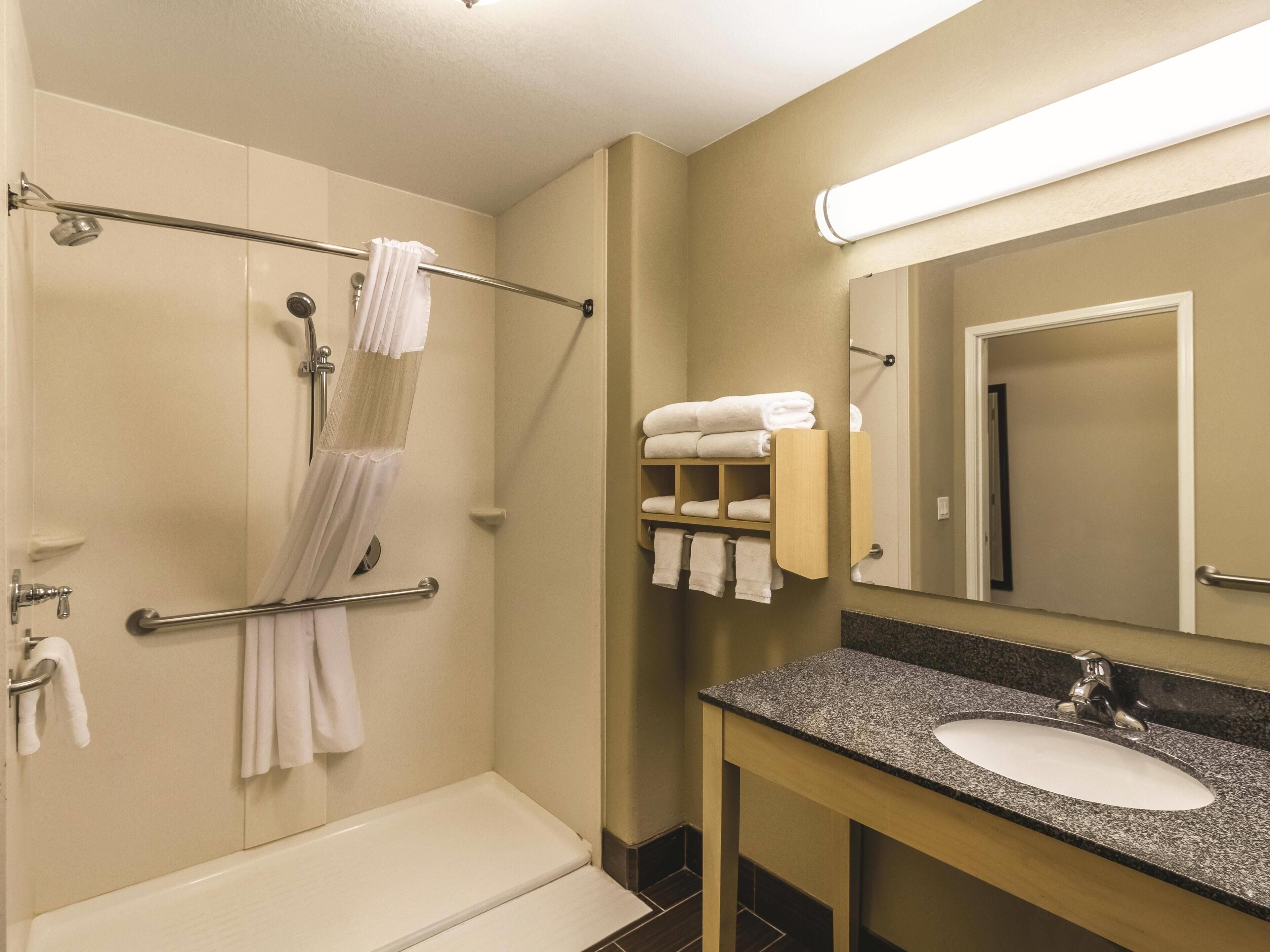 Een badkamer met een bad, een douche, een wastafelmeubel en een handdoekrek.
