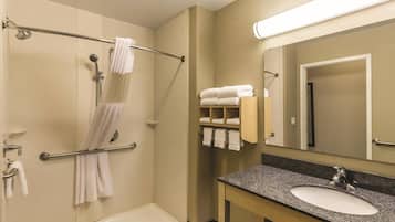 Un baño con bañera, ducha, tocador con lavamanos y un perchero para toallas.