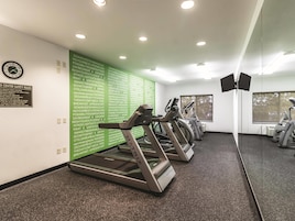 A gym with treadmills, a wall with motivational quotes, and a safety rule sign.