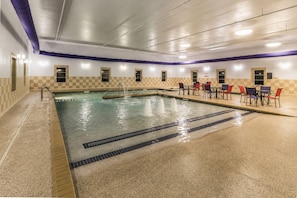An indoor swimming pool with a checkered wall design, a seating area with tables and chairs, and a tiled floor. - La Quinta Inn & Suites by Wyndham Fargo-Medical Center (Fargo)
