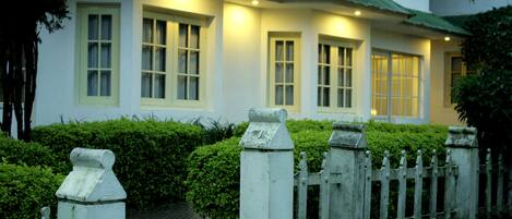 A white building with multiple windows and a white picket fence.