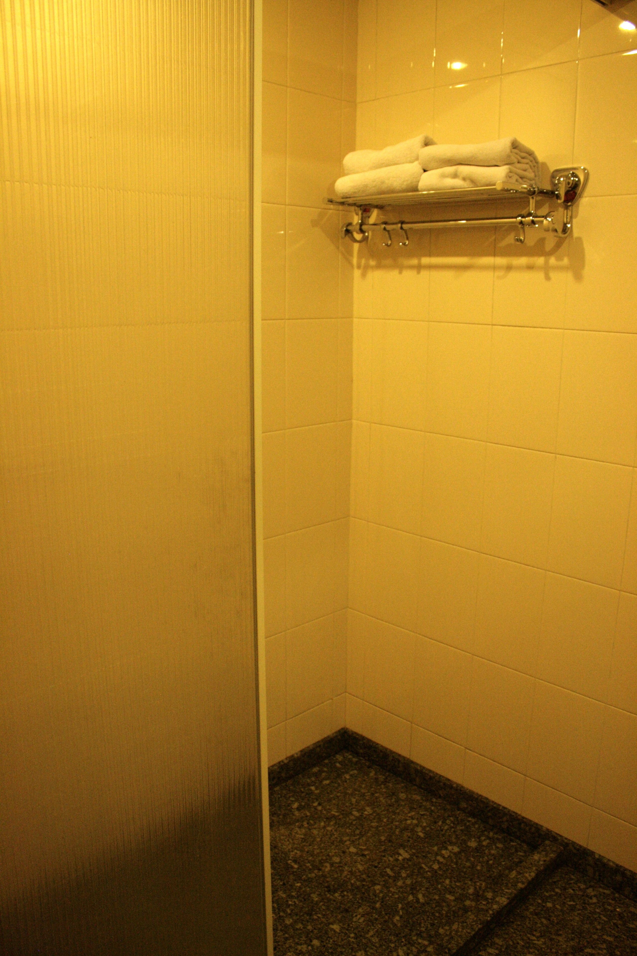 A bathroom with a tiled wall, a towel rack with folded towels, and a granite floor.