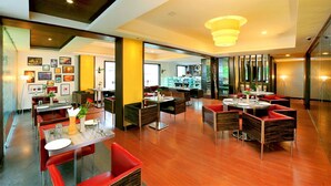 A modern restaurant with wooden flooring, red and black upholstered chairs, and a central dining area with round tables. - Eastend Munnar (Devikolam)