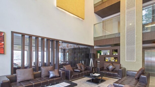 A spacious lobby with leather sofas, a coffee table, and a large mirror. - Eastend Munnar (Devikolam)