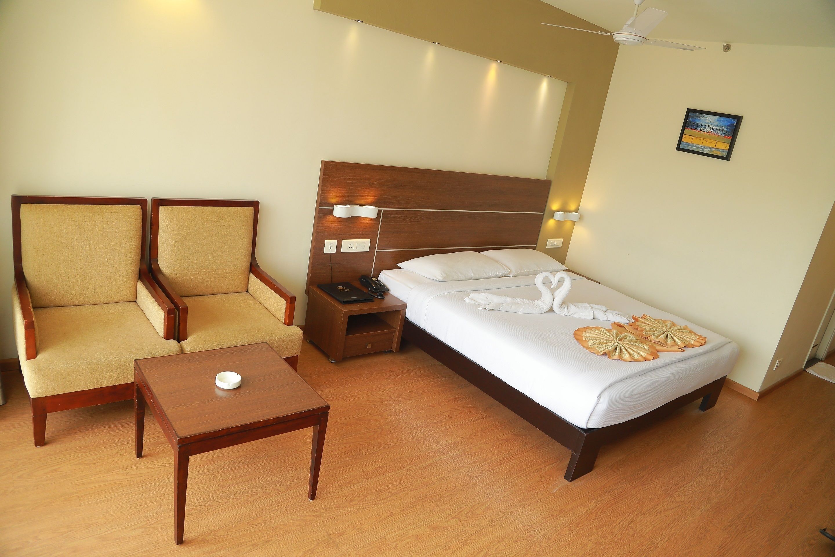 A hotel room with a bed, two armchairs, a nightstand, and a small table.