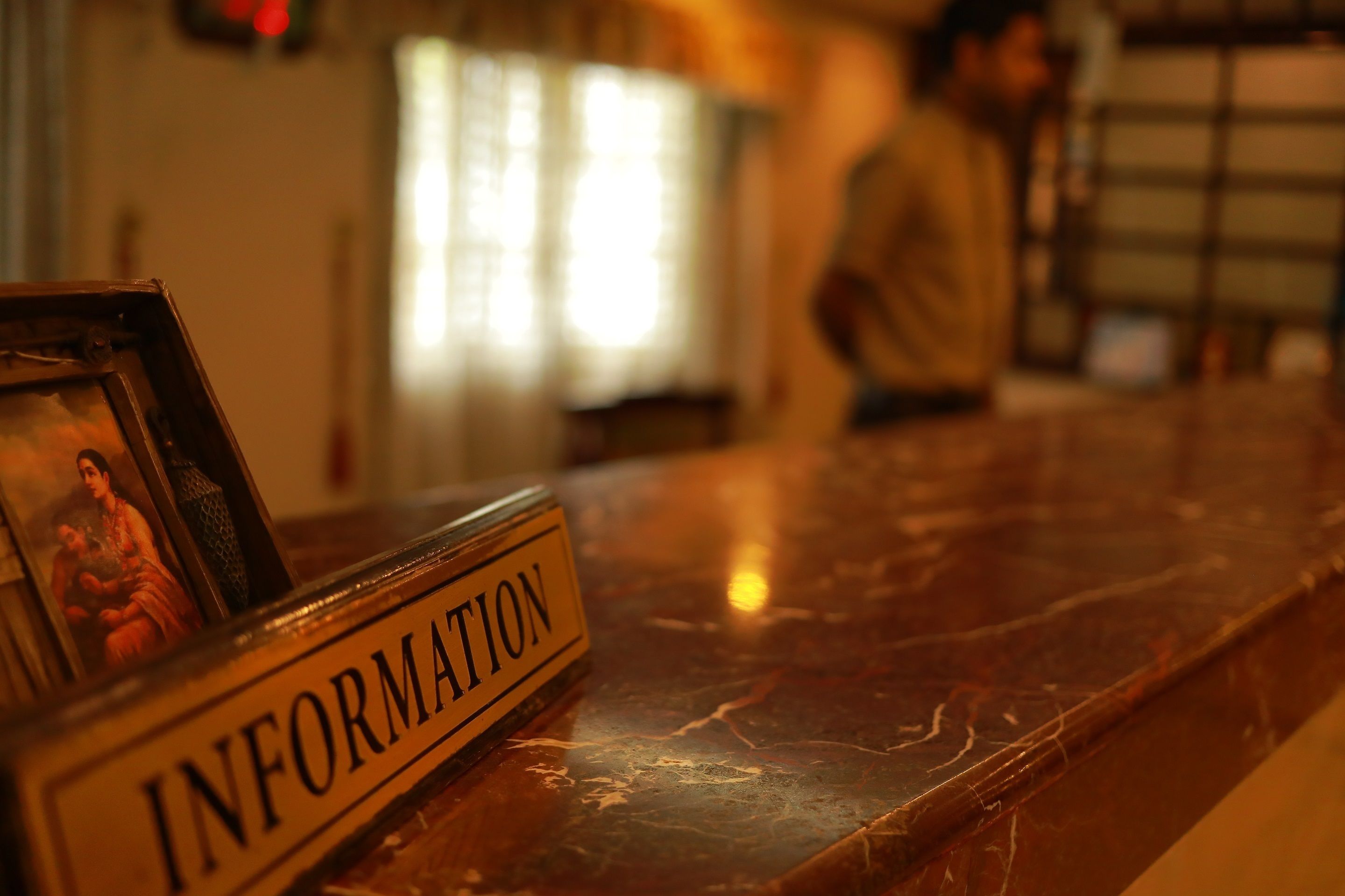 A marble reception desk with a sign labeled "INFORMATION" and a framed picture.