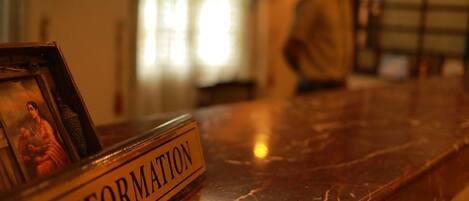 A marble reception desk with a sign labeled "INFORMATION" and a framed picture.