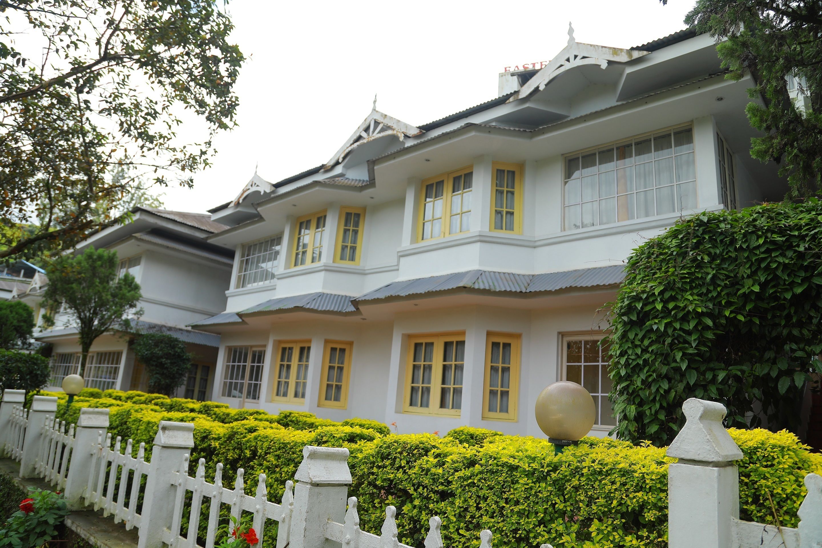 A traditional-style building with multiple windows and a white fence.