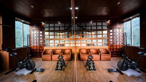 A mirrored gym with wooden walls, mirrored ceiling, and large windows. - Hill View Munnar (Devikolam)