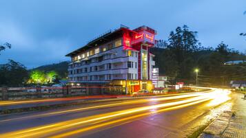 A multi-story hotel with a prominent red and white facade, multiple balconies, and a well-lit entrance.