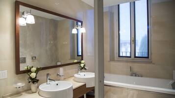 Une salle de bain moderne avec deux lavabos, un grand miroir et une baignoire.