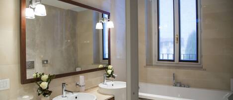 A modern bathroom with two sinks, a large mirror, and a bathtub.