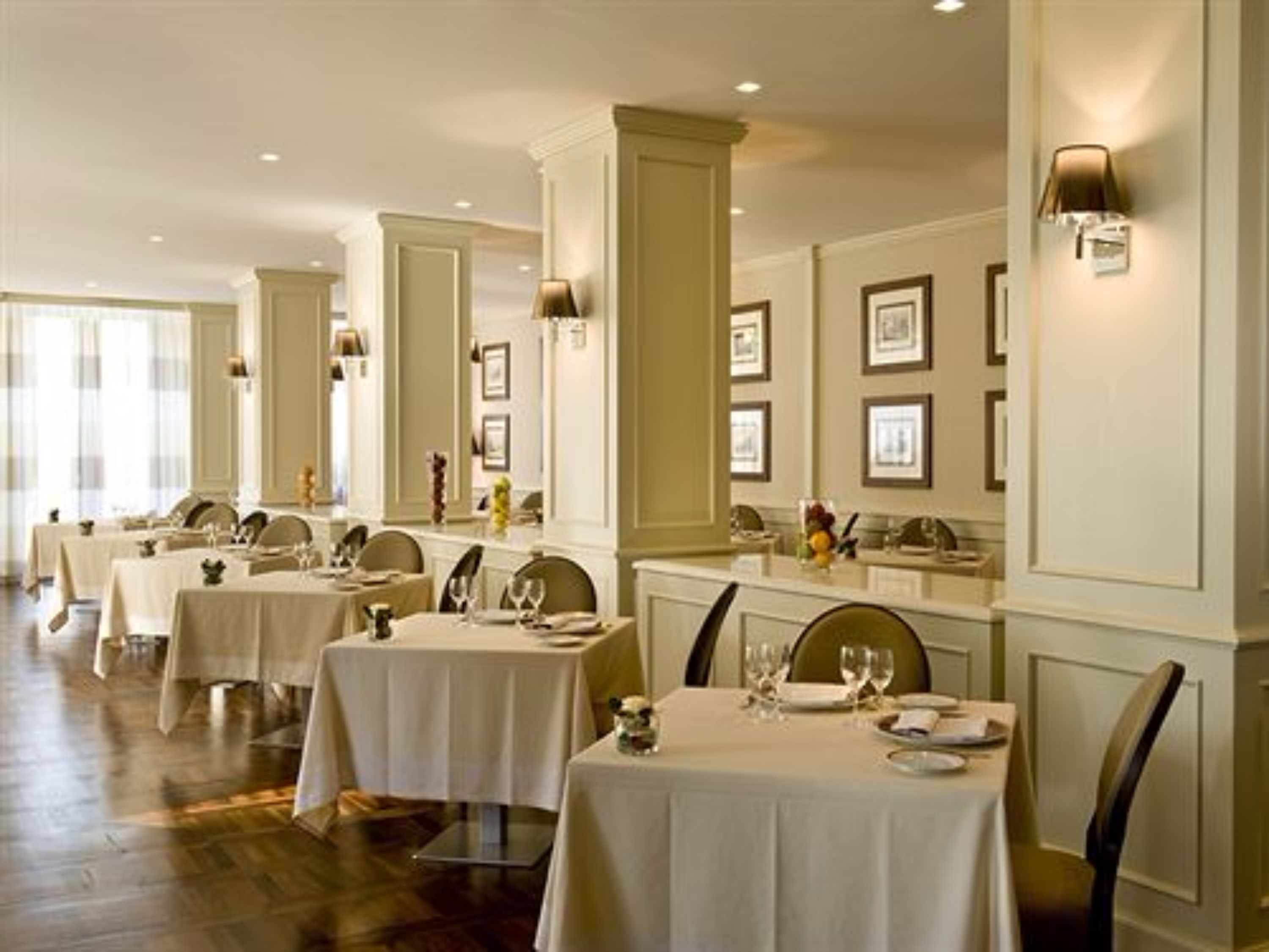 Ein Restaurant mit mehreren Tischen, jeder Tisch ist mit einer weißen Tischdecke und Stühlen gedeckt.