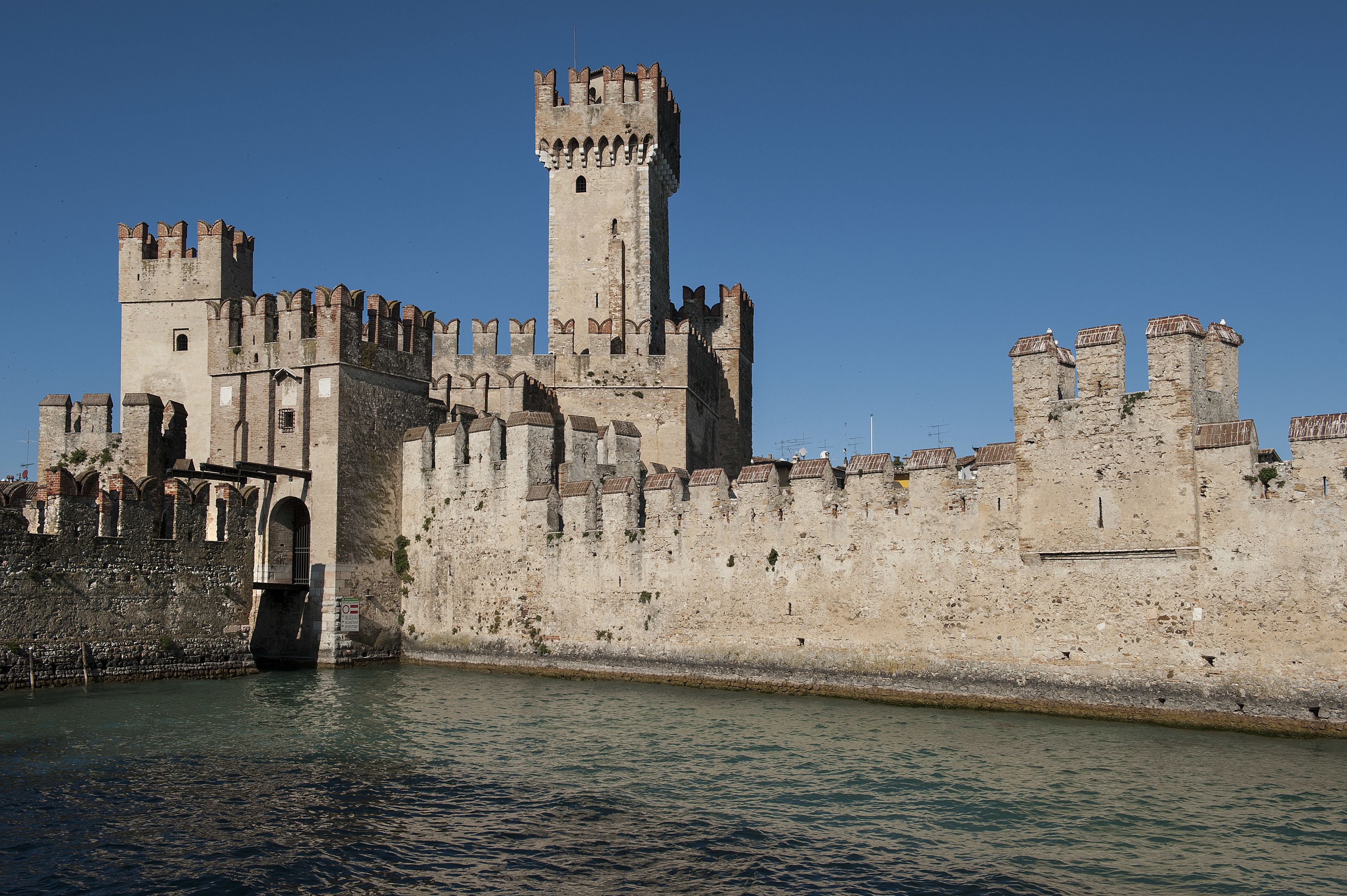 A historic castle with multiple towers and a fortified wall along a river.