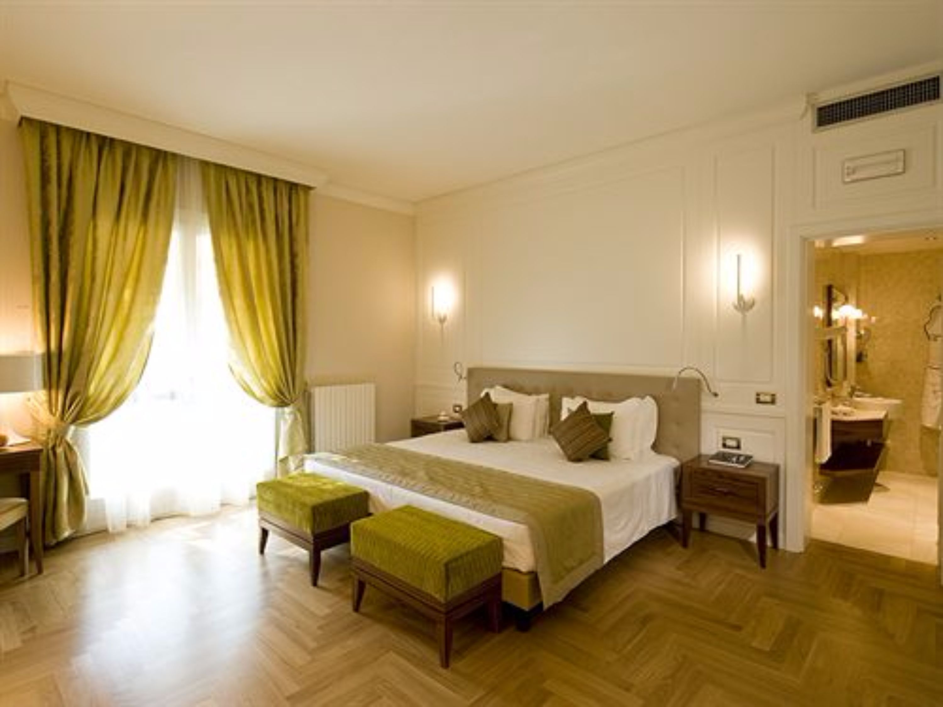 Un dormitorio de hotel con una cama grande, dos mesitas de noche, un espejo y una ventana con cortinas.