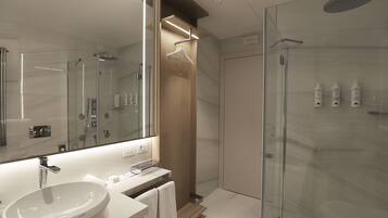 Un baño moderno con un espejo grande, un lavabo y una ducha con paredes de vidrio.