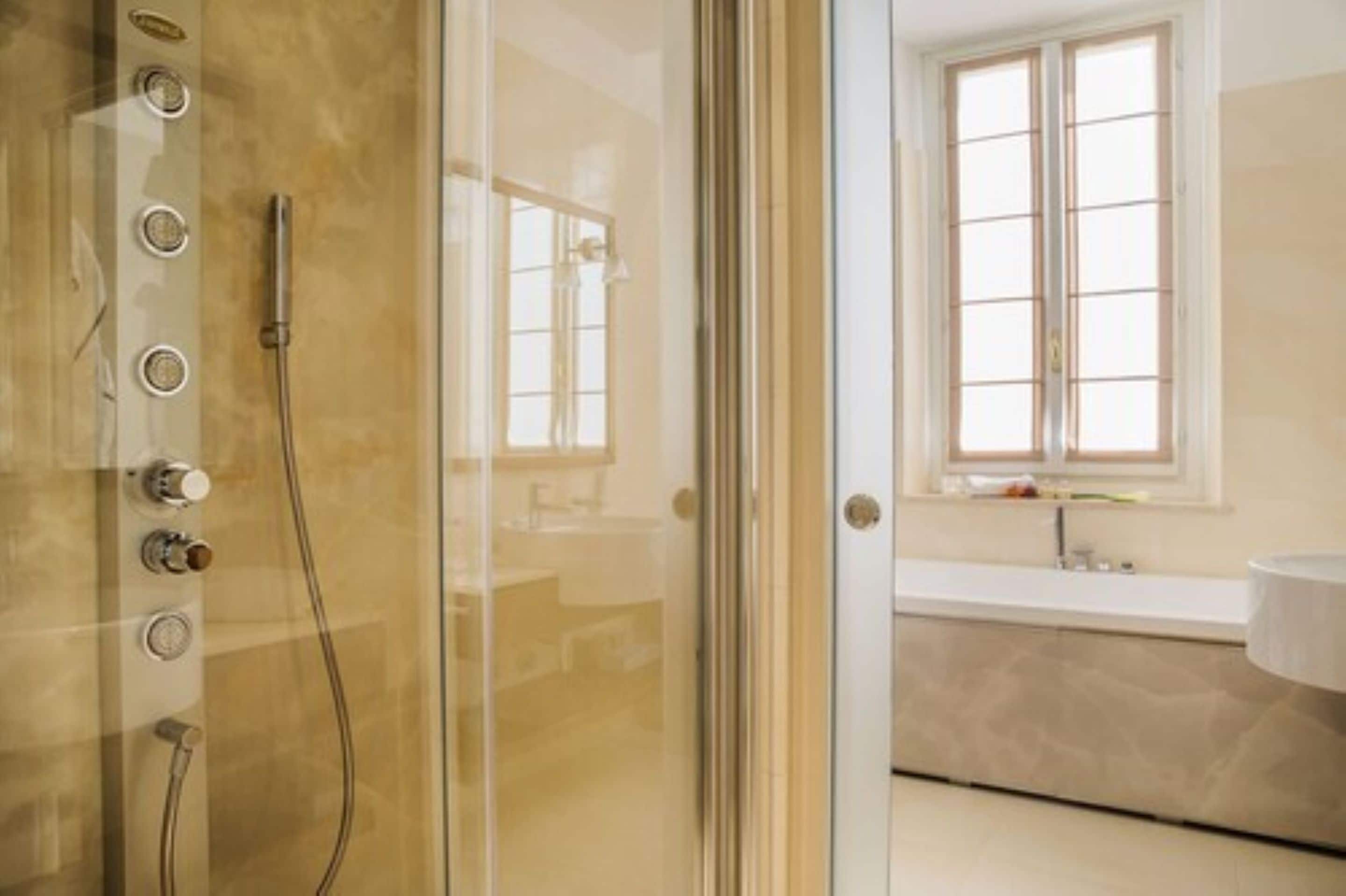 Een moderne badkamer met een douchecabine, een badkuip en een raam.