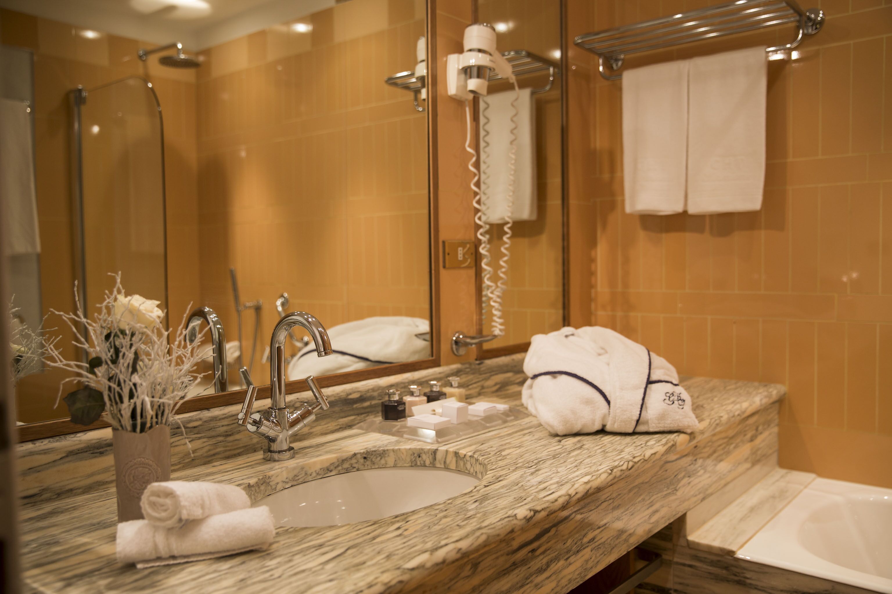 Un bagno con un lavabo in marmo, un asciugacapelli portatile e un porta asciugamani.