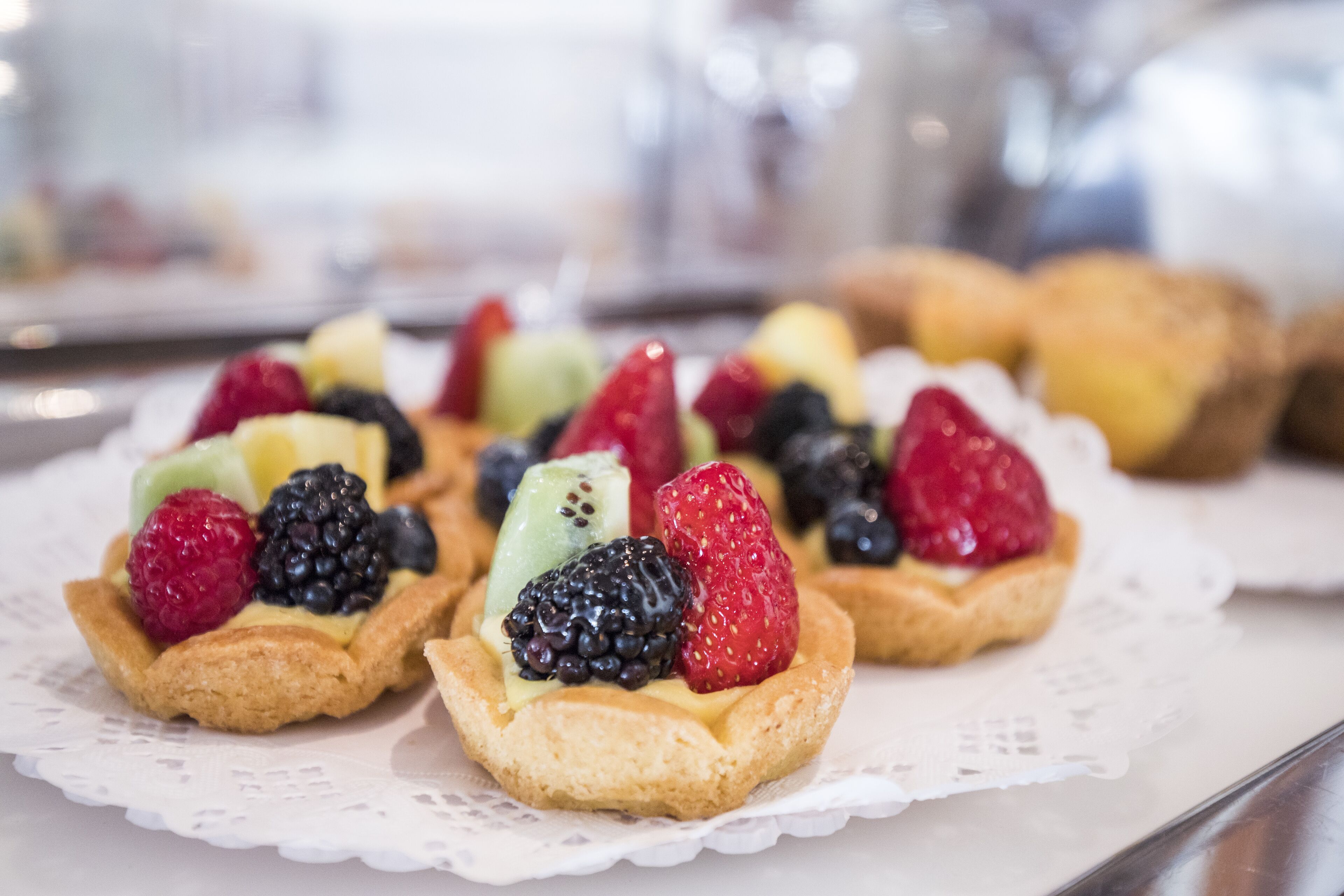 Un vassoio con tartine guarnite con frutta su un sottotavolo bianco.