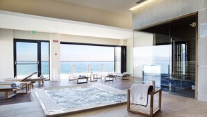 Ein Wellnessbereich mit Whirlpool, Liegestühlen und Blick auf das Meer.