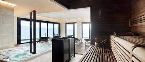 A modern spa area with a hot tub, seating, and large windows offering a view of the sea.