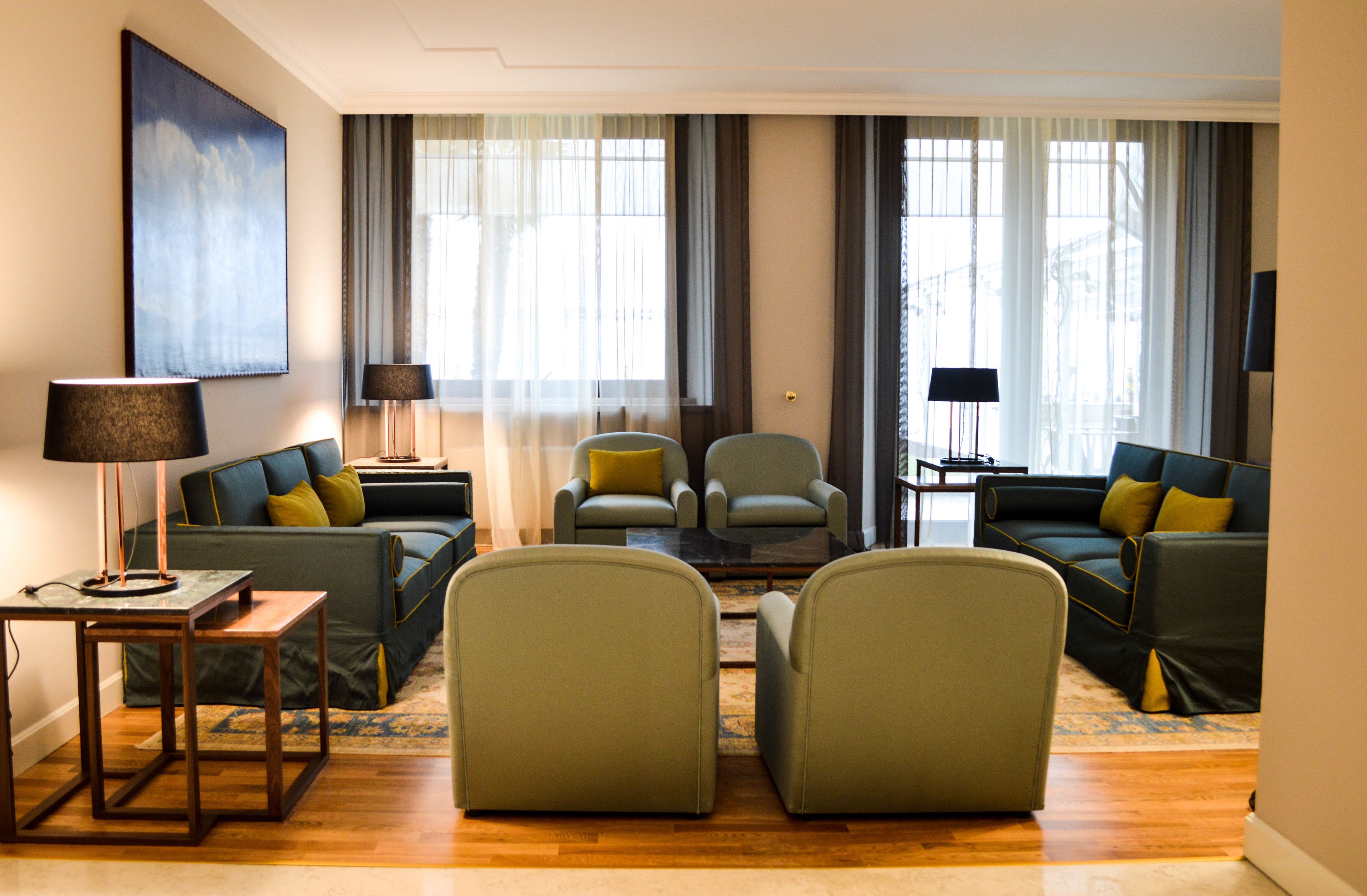 Una sala de estar moderna con un sofá, dos sillones, una mesita de centro y una lámpara.