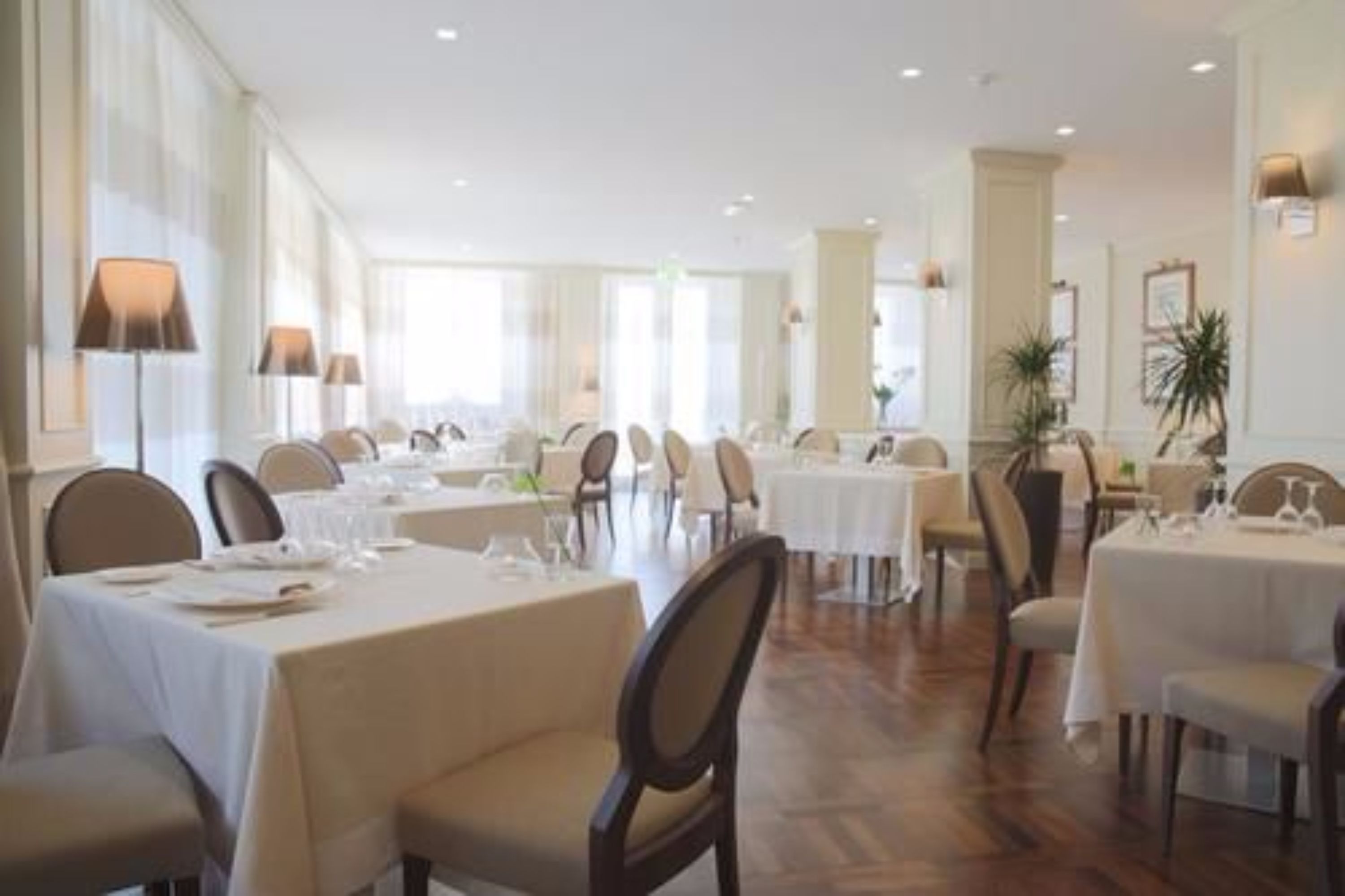 Un vaste espace dédié à la salle à manger, avec de nombreuses tables et chaises, de grandes fenêtres et un aménagement épuré et moderne.