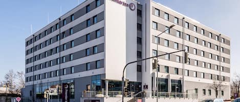 Un moderno edificio de hotel con un llamativo letrero de Premier Inn, varios pisos y una entrada visible con escaleras.