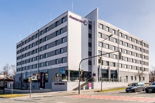 Un moderno edificio de hotel con un llamativo letrero de Premier Inn, varios pisos y una entrada visible con escaleras.