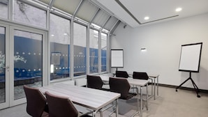 A conference room with glass walls, a whiteboard, and a projector stand. - Premier Inn Nürnberg City Nordost (Nuremberg)