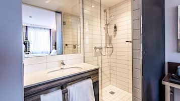 Un baño moderno con ducha de vidrio, tocador doble y un espejo grande.