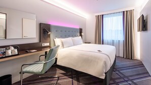 A hotel room with a bed, a desk with a chair, a television, and a window with curtains. - Premier Inn Nürnberg City Nordost (Nuremberg)
