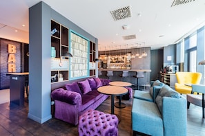 A modern lounge area with a bar, seating arrangements, and a visible bar counter. - Premier Inn Nürnberg City Nordost (Nuremberg)