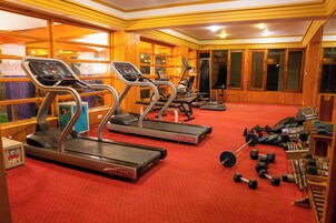 Un gimnasio con cintas de correr, mancuernas y máquinas de pesas.
