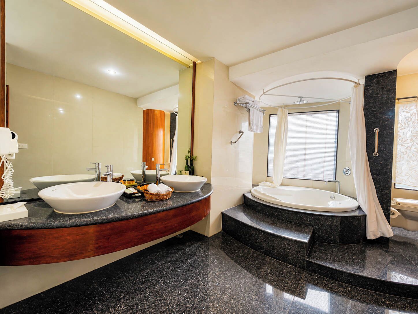 Un baño moderno con dos lavamanos, una bañera y un espejo grande.